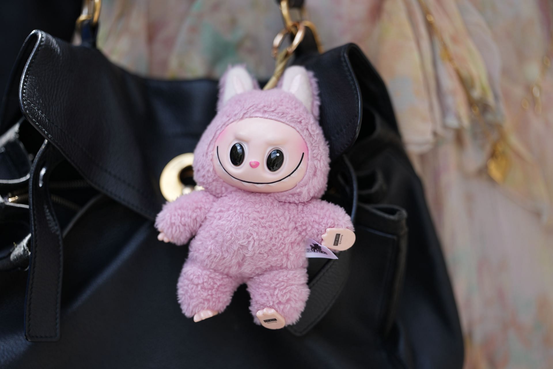 A Labubu doll on a handbag (Image via Getty)